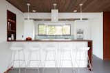 Klopf Architecture and Jesse Ososki Art remodeled an existing Eichler atrium home into a brighter, more open, and more functional version of its original self. 

The goals were to preserve the Eichler look and feel without the need to strictly adhere to it. The scope of work included re-configuring the master bedroom/bath, the kitchen, and the hall bath/laundry area, as well as updating interior finishes throughout to be more sophisticated.

The owners are detail-oriented and were very involved in the design process, down to the selection of lighting controls and stainless steel faceplates.Their design aesthetic leans toward the Scandinavian — light and bright, with simple straight lines and pure geometric shapes.

The finish flooring is large porcelain tile (24” x 24”) in a neutral grey tone, providing a uniform backdrop against which other materials can stand out. The same tile continues into the shower floor (with a different finish texture for slip-resistance) and up the shower/tub walls (in a smaller size). Heath Classic Field ceramic tile in Modern Blue was used sparingly, to add color at the hall bath vanity backsplash and at the shampoo niches in both bathrooms. Back-painted soda glass in pale blue to match the Heath tile was used at the kitchen backsplash. This same accent color was also used at the front entry atrium door. Kitchen cabinetry, countertops, appliances, and light fixtures are all white, making the kitchen feel more airy and light. Countertops are Caesarstone Blizzard.

The owners chose to keep some of the original Eichler elements:  the concrete masonry fireplace; the stained tongue-and-groove redwood ceiling decking; and the luan wall paneling. The luan paneling was lightly sanded, cleaned, and re-stained. The owners also kept an added element that was installed by a previous owner: sliding shoji panels at all bedroom windows and sliding glass doors, for both privacy and sun control. Grooves were cut into the new tile flooring for the shoji panels to slide in, creating a more integrated look. Walnut was used to add warmth and contrast at the kitchen bar top and niche, the bathroom vanities, and the window sill/ledge under the kitchen window.

This Burlingame Eichler Remodel is a 2,121 sf, 4 bedroom/2 bath home located in the heart of Silicon Valley.

Klopf Architecture Project Team: John Klopf, Klara Kevane and Yegvenia Torres Zavala
Contractor: Jesse Ososki Art 
Structural Engineer: Emmanuel Pun
Photography ©2018 Mariko Reed
Location: Burlingame, CA
Year completed: 2017



