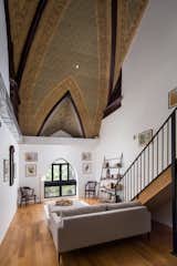 Living Room, Sofa, Chair, Bookcase, Floor Lighting, Lamps, Medium Hardwood Floor, Rug Floor, and Ottomans  Photo 4 of 14 in Rent One of These Stunning Lofts in a Converted Brooklyn Church from St Marks from @nooklyn