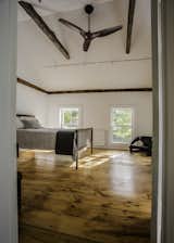 Salvaged hand hewn ceiling beams complement the original beams now exposed along the entire perimeter of the walls in the master bedroom. Ceiling fan by Haiku.  Photo 5 of 14 in twist farmhouse by Tom Givone