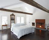 In the master bedroom, a vaulted ceiling is anchored by a pair of centuries-old hand hewn beams. An oversized wood burning fireplace, faced with a panel of oxidized Cor-Ten steel, warms the space.
