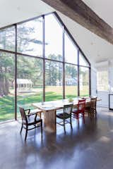 Curtain wall of skyscraper glass in kitchen, 22 feet tall, frames views of the water, gazebo, apple trees, and barns.