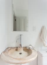 White concrete walls and a century-old city water fountain, turned sink, grace the first floor bathroom.