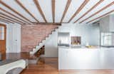 Custom finishes in anodized aluminum meet original exposed ceiling beams and brick walls in the floor-through kitchen.
