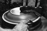 This in an archival photograph showing a plate being formed in the 1950's on a manual jiggering machine.