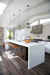 Kitchen, Dark Hardwood Floor, Pendant Lighting, Range Hood, Range, Undermount Sink, and White Cabinet  Photo 5 of 10 in 10 Open Kitchen Solutions That Will Get Things Cooking from Kitchen Island Modern Lighting Adds Minimalist Feel to California Home