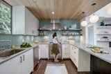 A trio of Solitaire pendants in Opaline glass hangs above the kitchen island. The milky color of our opaque glass emits a soft glow, which is further diffused by frosted bulbs. This white hue complements the clean, minimalist interior while turquoise and yellow accents add a subtle pop of color. With stylish, sleek appliances, open layouts, and Niche glass pendant lights, an elegant display becomes the center of attention in this modern kitchen. 