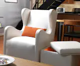 Modern upholstered Vola glider in white by Monte Design with a orange pillow