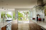 Kitchen, Ceramic Tile Backsplashe, Pendant Lighting, Cooktops, Light Hardwood Floor, Undermount Sink, Range Hood, Range, Quartzite Counter, and Wood Cabinet Kitchen out to patio and views  Photo 5 of 14 in Windermere Midcentury Renovation +ADU by CAST architecture