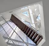 Staircase, Metal Railing, Wood Tread, and Glass Railing The home's circulation is organized around a three-story triangular atrium capped with a glass pyramid skylight, flooding the interior with natural light.  Photo 9 of 22 in Skylight House by dSPACE Studio