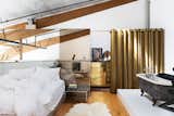 Breer designed a glass wall to section the closet and act as a headboard in the bedroom area, where a black clawfoot tub is across from the bed. The gold dresser is vintage Sarreid.