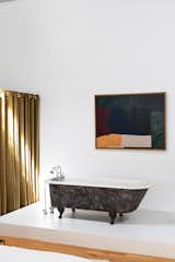 An abstract painting by modern artist Robert Breer, the designer's father, hangs above a black clawfoot tub.