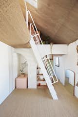 A steel ladder leads between a double-height common area and the mezzanine above. An original archway became built-in storage that hides an existing downpipe. 