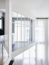 The glass walls of the mezzanine let sunlight flood the upper-level private spaces, including the bedroom and the bath.