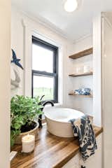 Horizontal shiplap siding offsets coffee-colored wood counters on the vanity in the bath.