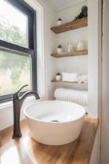 White walls and natural wood counters and shelves create a fresh aesthetic in the bathroom.