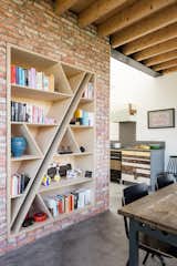 In the dining area, a custom birch bookcase is inset into a partial wall of brick that was salvaged from the previous house that stood on the lot. 