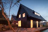 Clad in wax-covered pine, this 645-square-foot dwelling in Amsterdam is striking on the outside and endlessly charming on the inside. At night, the large windows give the compact home a lantern effect.