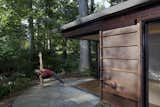 Glass pocket doors slide away, opening the cabin to its wooded surround. Bluestone pavers on the exterior contrast with the warm tone of the Cor-Ten steel siding.