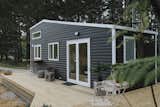 The tiny home is clad with black-painted vinyl siding and bright white trim. "The client wanted to make the most of the outdoor setting and asked us to build a removable outdoor bar under the kitchen window," says designer Gina Stevens.&nbsp;