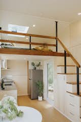 The loft bedroom is situated above the kitchen. The staircase is outfitted with drawers and a tall cabinet for cooking tools.