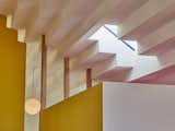 Sundius and Ichiki employed a white-painted, stepped ceiling that's made from drywall and reflects a bright, yellow wall and door and the pink tone that accents the bathroom skylight.