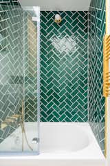Saules by Hoch Studio shower with green herringbone-pattern tiles and gold hardware