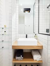 Bath, Wood, Vessel, Corner, Porcelain Tile, Wall, Porcelain Tile, and Alcove "I optimized every inch of space in the bathroom," says Petillaut, who employed a black-and-white palette and geometric lines that make the room feel more voluminous.   Bath Porcelain Tile Wood Vessel Wall Photos from Budget Breakdown: A Muddled Parisian Pad Gets a Sleek Makeover for $117K