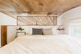 A wood screen lends privacy in the loft-style bedroom while still allowing for air to flow in and out of the space.