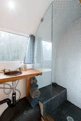 In the bathroom, hexagonal mosaic tile covers the floor and the shower walls. The vanity is made from a maple slab, and the sink and the fixtures are copper.