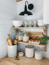 An industrial-style metal sconce, ceramic tableware, and wood countertops lend a farmhouse aesthetic to the kitchen.
