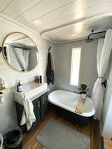 Bath, Laminate, Freestanding, Ceiling, and Undermount Saul outfitted an antique, cast-iron clawfoot tub ($200) with a rainfall showerhead ($80) in the bathroom.  Bath Laminate Photos from Budget Breakdown: Two Travel Therapists Build a Tiny Home-on-Wheels for $24K