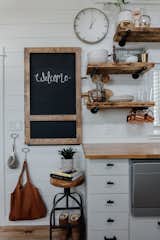 A wood-framed chalkboard folds down from a wall in the kitchen and provides more counter space and a dining area. The open wood shelving was crafted from a beloved table that did not fit in the tiny home.