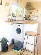 A panel in the kitchen cabinetry conceals a small washing machine beneath the counter.