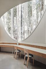 The window in the open-plan kitchen/dining space takes the form of an inverted arch, framing treetops around the site.