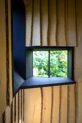 Black-painted plywood window frames contrast with the pale tone of the layered Ash wood siding.