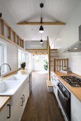 The interior of the tiny home, which features a sleeping loft above the living room, is finished with vinyl flooring and white pine walls.