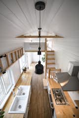 Kitchen, Laminate, White, Ceiling, Range Hood, Wood, Vinyl, Drop In, and Cooktops Ceilings that are over 10 feet tall provide a feeling of airiness for the tiny home.  Kitchen Cooktops Range Hood Drop In White Photos from One Family’s 416-Square-Foot Digs Expand the Limits of Tiny Home Living