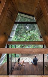 Outdoor, Back Yard, Trees, Wood Patio, Porch, Deck, and Shrubs Situated on the banks of a small river, the two-level cabin opens to the outdoors via a glass wall and folding glass doors on the rear facade.  Photos from This Carbon-Negative Cabin in Ecuador Sits Lightly in a Tropical Paradise