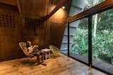 Living Room, End Tables, Wall Lighting, Medium Hardwood Floor, and Chair Perforated plywood walls in the living area facilitate cross ventilation.  Photos from This Carbon-Negative Cabin in Ecuador Sits Lightly in a Tropical Paradise