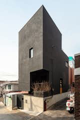 The exterior of the tall and narrow home is sided with black-painted stucco.
