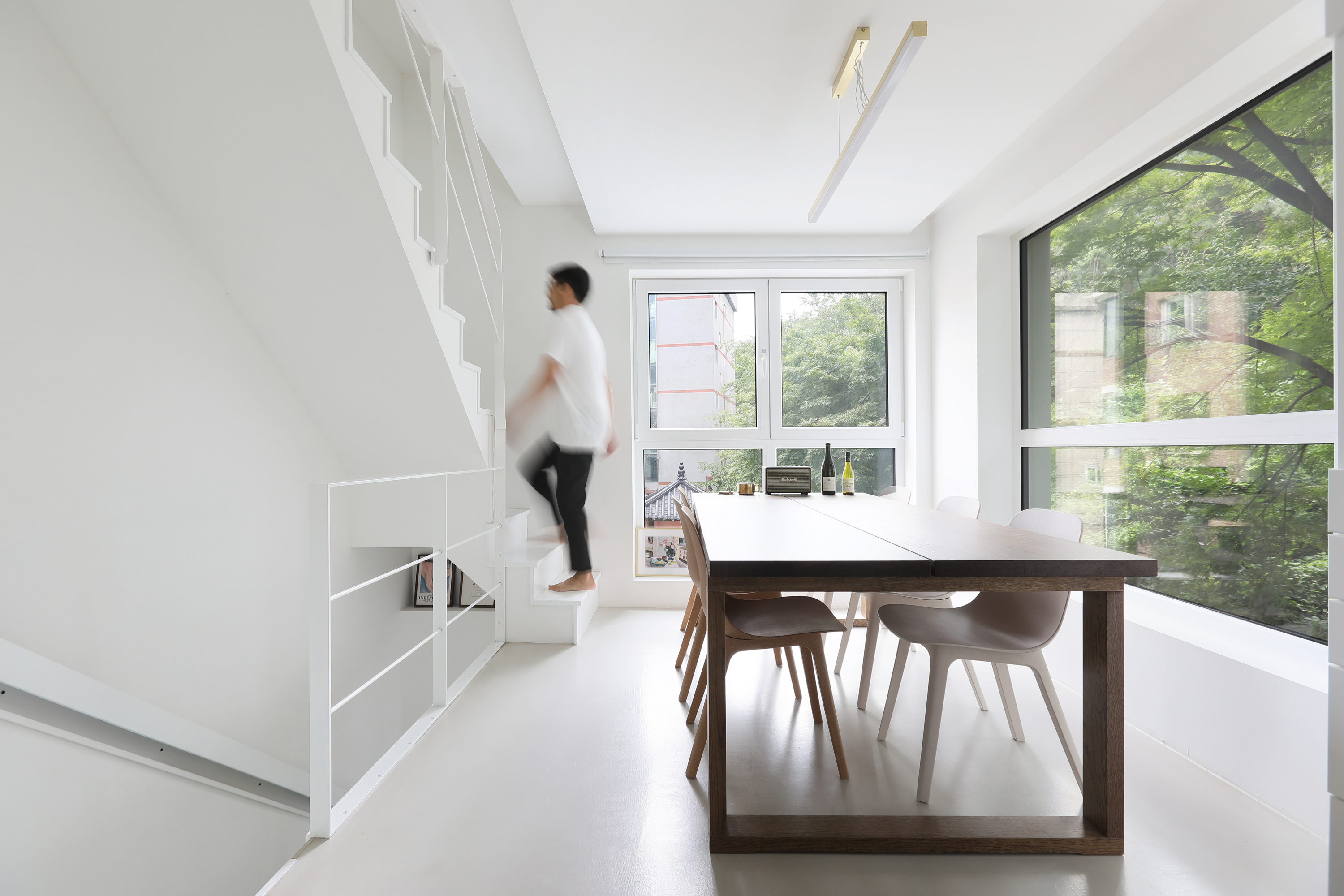 Seroro House kitchen and dining space with white plasterboard walls and treetop views in Seoul