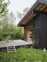 Architects Jean-Baptiste Barache, Sihem Lamine, and Pierre Gourvennec of Arba designed this 215-square-foot cabin in Normandy, France, for a married couple who will eventually use the retreat as their retirement home. The blackened timber–clad dwelling is marked by large glass doors layered with wood slats that slide open and connect the home to its lush landscape.