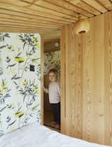 Sliding wood doors close off the loft-style main bedroom, where botanical-print wallpaper lends a whimsical note.