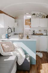 The couple spent almost a year and a half—and about $40,000—remodeling their compact home on wheels. They covered the cracked walls with shiplap, and in the living room they added a flip-up table/desk, removed a roof hatch and an artificial plant wall, and replaced the existing pink sofa with a built-in gray one that converts to a queen-size bed with storage space underneath.