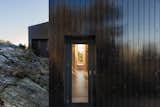 The bedrock that the cabin pushes up against creates a feeling of being nestled. A passageway with glass doors at either end floods the interior with sunlight and glimpses of the natural surround.