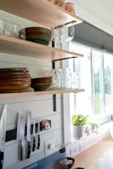 A magnetic strip that holds knives and other small cooking accessories is attached to the shiplap wall in the kitchen, helping to preserve space.