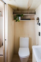 A custom plywood-and-aluminum door slides into the wall, providing access to the bathroom, which is also finished with plywood.