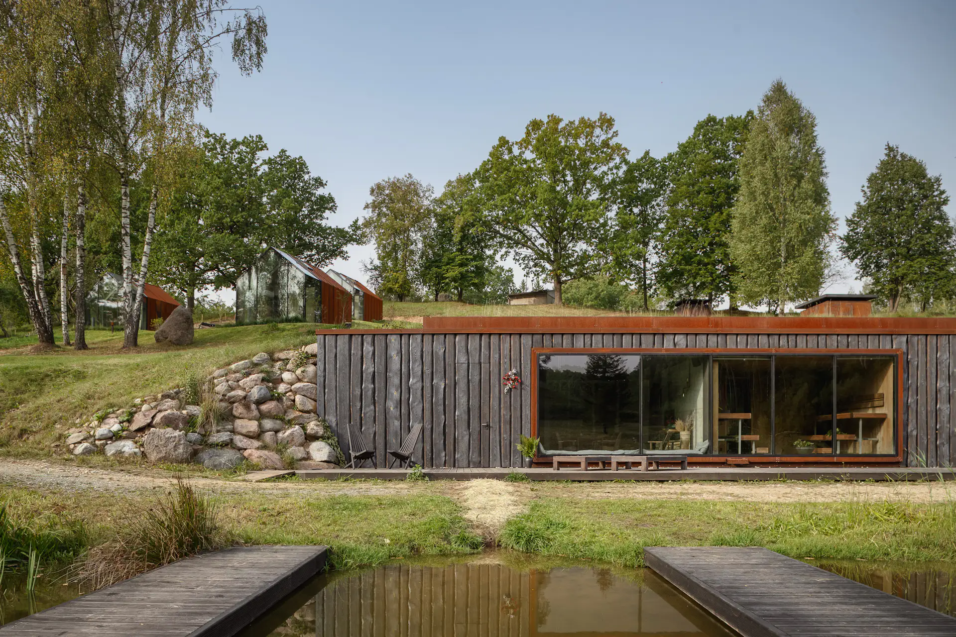 Tetere-Sulce created a glass facade for the front of the sauna building, which is built into the hillside and overlooks the ponds.