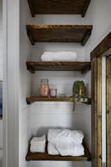 Open shelving serves as a linen closet between the bathroom and the main bedroom.