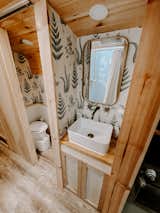 Van outfitted the bathroom with an open shower and a raised ceiling, and opted to put the vanity in the hallway. Botanical-print wallpaper dresses the walls of the vanity area and the separate space that Van built for the compostable toilet.&nbsp;